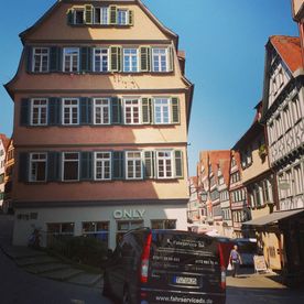 Großraumtaxi vor einem traditionellen Haus mit vielen Fenstern